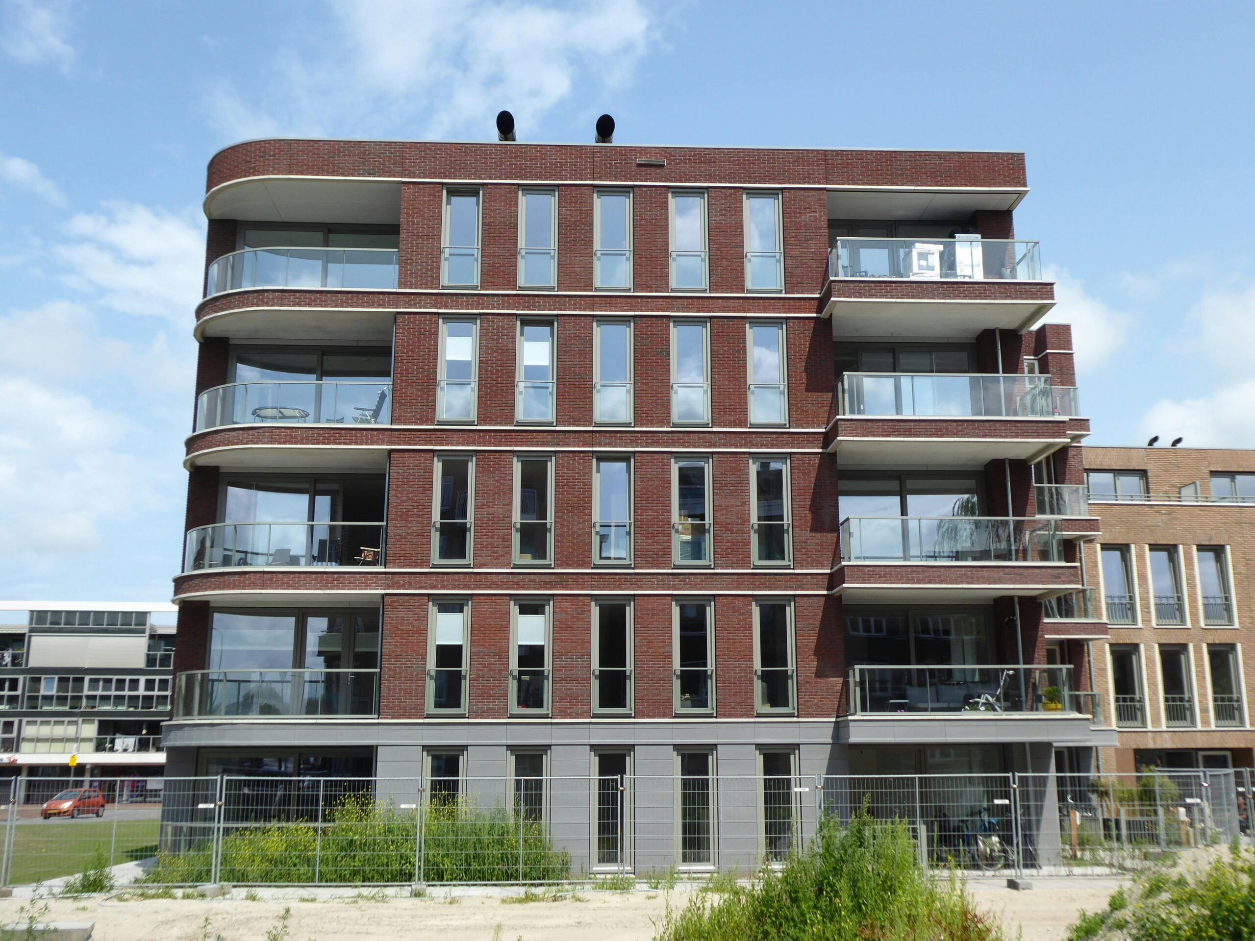Contemporary multi-story residential building with glass balconies and a stylish brick facade.